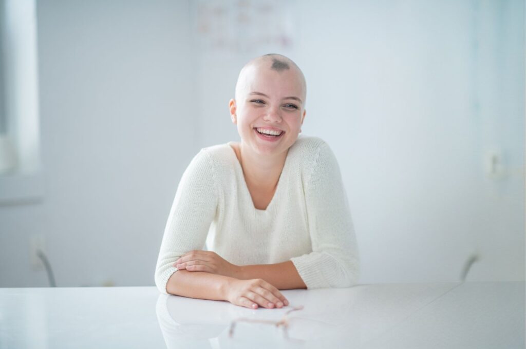 Young woman with alopecia smiles sitting at table