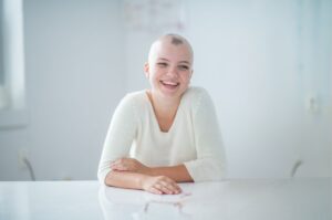 Young woman with alopecia smiles sitting at table